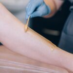 The specialist depilates the hair with wax on the leg